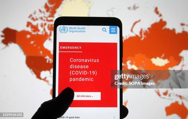 In this photo illustration, World Health Organization website is seen displayed on a smartphone with a background of a map showing the Covid-19...