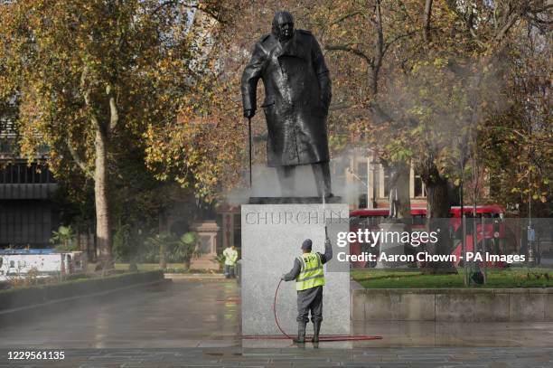 Workman uses a water jet spray to clean the statue of Sir Winston Churchill in Parliament Square, London.