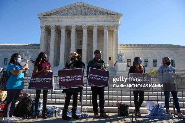 Demonstrators hold signs in front of the US Supreme Court in Washington, DC, on November 10 as the high court opened arguments in the long-brewing...