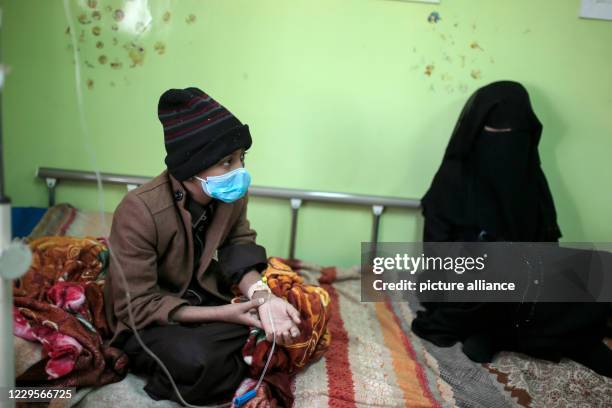 November 2020, Yemen, Sanaa: A Yemeni boy who has cancer, sits on a bed as he receives cancer treatment next to his mother at the Oncology Centre in...