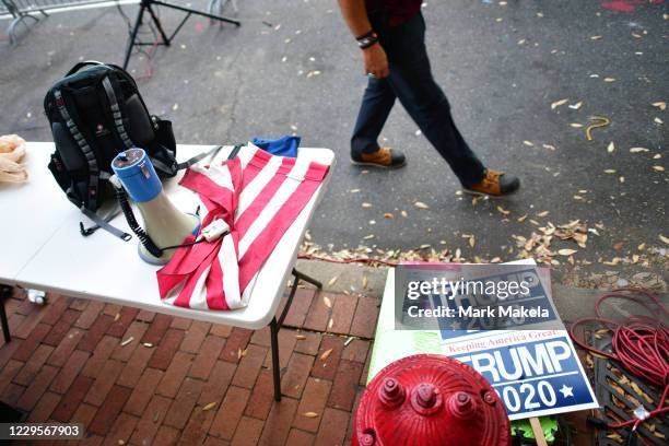 Supporter of President Donald Trump walks past campaign signs, a U.S. Flag, and a bull horn while demonstrating outside of where votes are still...