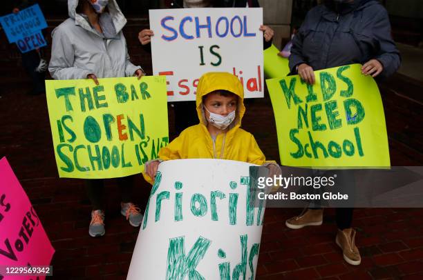 An Eliot K-2 School first grader holds a sign that says, "Prioritize Kids" during a rally outside of Boston City Hall in Boston called "Stand up for...