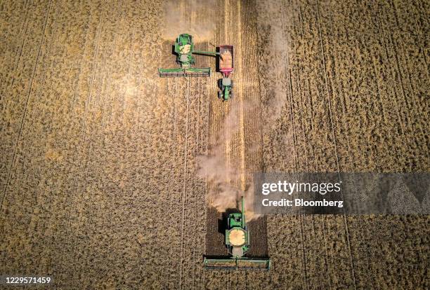 Farmer operates a combine harvester as he unloads wheat into a grain cart during a harvest at a farm near Gunnedah, New South Wales, Australia, on...