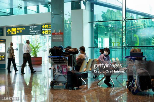 Travellers sit and wait for their flight at the departure hall of Changi Airport Terminal 1 on November 11, 2020 in Singapore. Singapore and Hong...