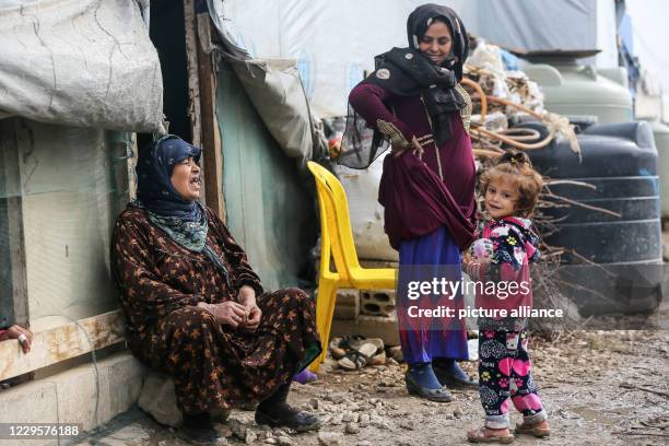 November 2020, Syria, Bar Elias: Syrian refugees sit outside their tent at al-Fares camp in Lebanon's Bekaa valley. Syrian President Bashar al-Assad...
