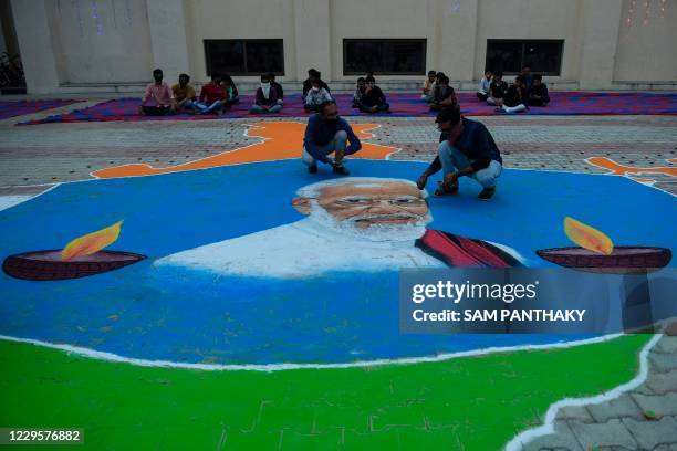 Artists Kalpesh Budheliya and Mahesh Chauhan give finishing touches to a Rangoli, a floor painting made with coloured powder, depicting Indian Prime...