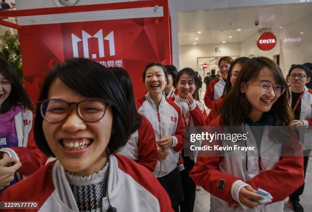 Workers from Chinese e-commerce giant JD.com react as they gather together for photos during a break for Singles Day in the lobby at the company's...