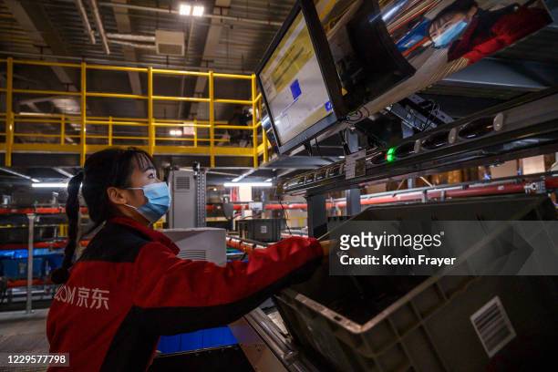 Worker from Chinese e-commerce giant JD.com works on an automated sorting machine at the company's main logistics hub during an organized tour for...