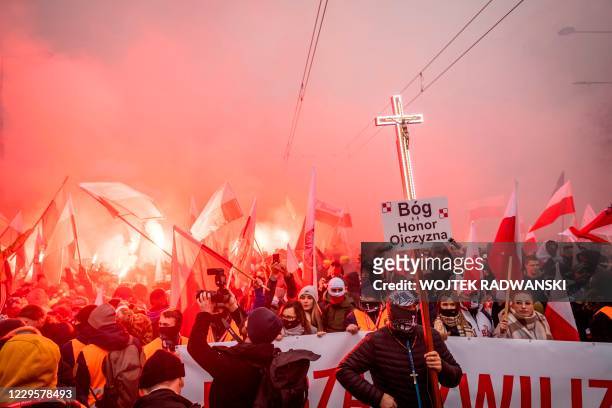 Man holds a cross with a placard reading "God, Honour, Homeland" as Polish far-right supporters march through the centre of Warsaw to mark the...