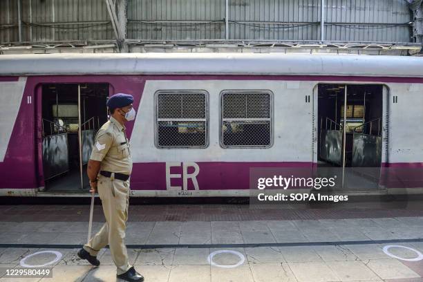 Police officer patrols the train station as Local trains resume their service in west Bengal after being closed for nearly 8 months due to...