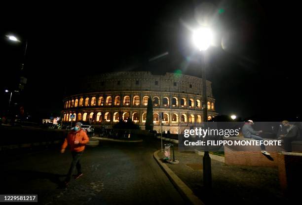 People wearing protective face masks are seen near the Colosseum in Rome on November 11 during the government's restriction measures to curb the...