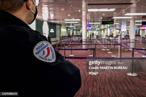 Police officer waits at the customs counter of Paris Roissy Charles De Gaulle airport, on November 12, 2020.