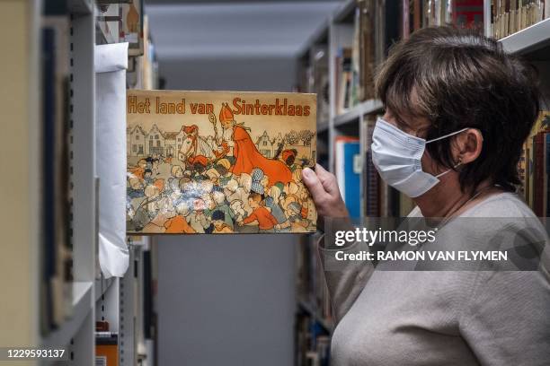 An employee of the Amsterdam Public Library shows a book with Sinterklaas and Zwarte Piet in Amsterdam, on November 12, 2020. - The library is...