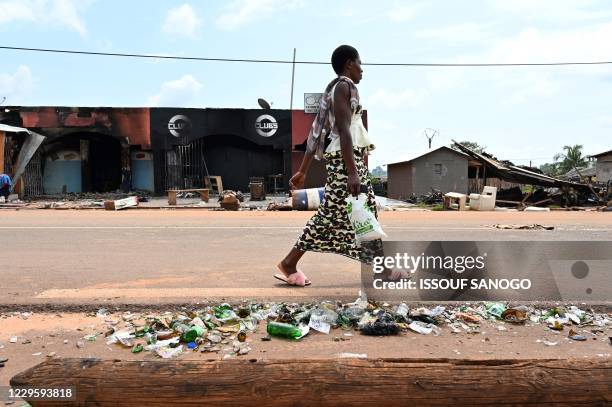 Woman walks past burnt shops in a street of M'Batto on November 12 after inter-community violences broke out following the country's presidential...