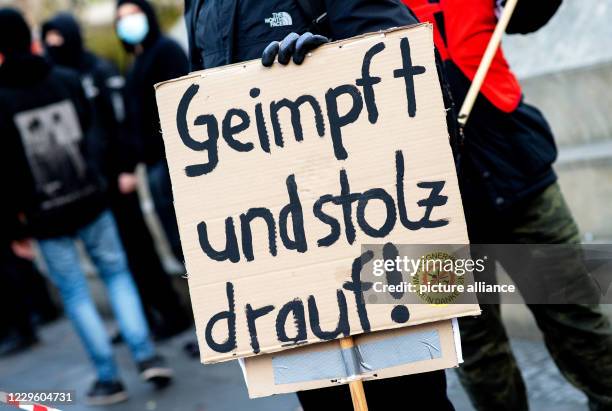 November 2020, Lower Saxony, Hanover: A participant of a counter-demonstration stands on the opera square with a cardboard sign with the inscription...