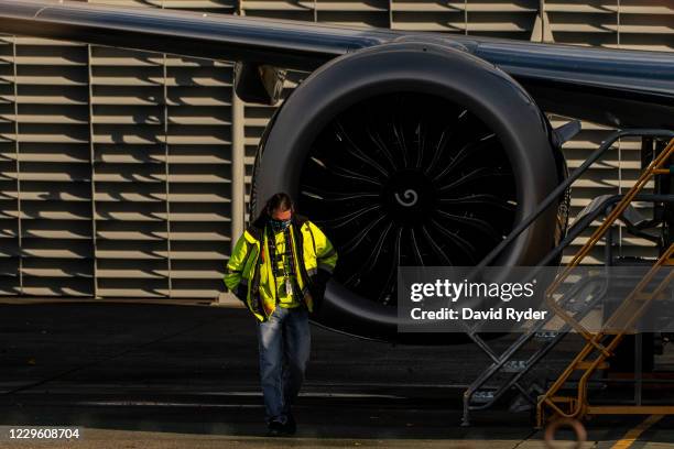 Worker walks by the engine of a Boeing 737 Max airplane as it sits parked at the company's Renton production facility on November 13, 2020 in Renton,...