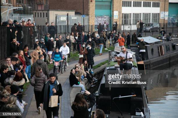 Crowds gather to listen to a busker playing on Regents Canal during the second coronavirus national lockdown on November 7th 2020 Hackney, East...