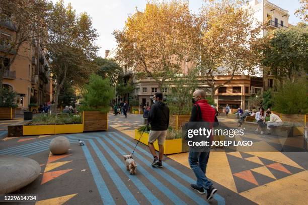 People walk in a pedestrian area as part of an expansion of the "superilla" plan promoting cycling and car-free zones in Barcelona on November 14,...