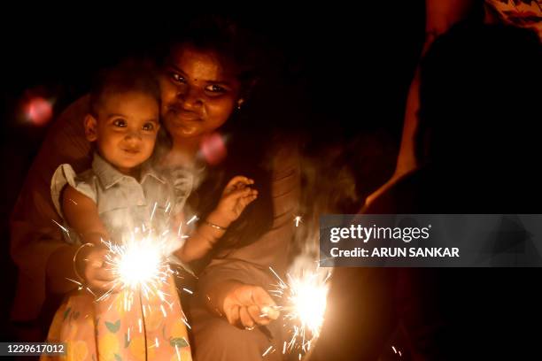 Mother along with her daughter light a sparkler during Diwali, the Hindu Festival of Lights, in Chennai on November 14, 2020.