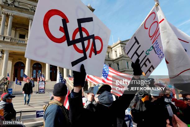 Counter-protester displays placards during a "Stop the Steal" rally in support of US President Donald Trump at the Michigan State Capitol, on...