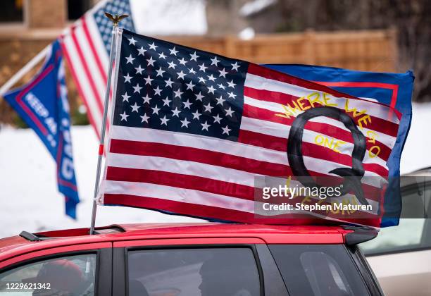 Car with a flag endorsing the QAnon drives by as supporters of President Donald Trump gather for a rally outside the Governor's Mansion on November...