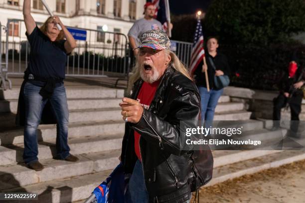 Supporter of President Trump yells at counter-protesters after a flashlight was shone in his face during a rally to protest the election results...