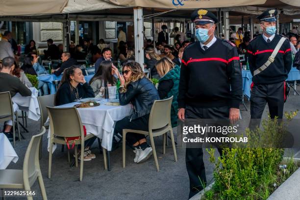 An Italian carabinieri patrol next to people in a restaurant on the seafront. Italian Government has decided the closure of all unnecessary...