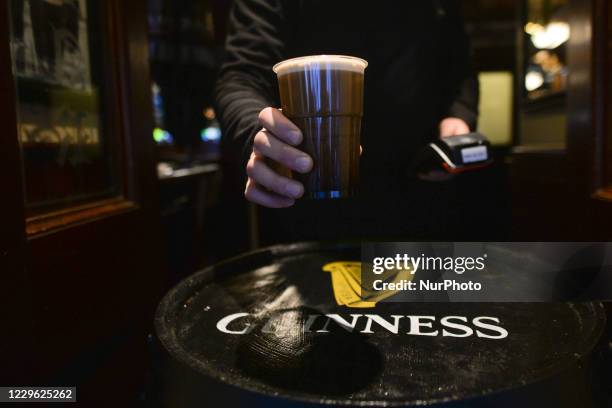 Pint of Guinness in a plastic cup served in The Ha'Penny Bridge Pub in the center of Dublin. On Saturday, November 14 in Dublin, Ireland.