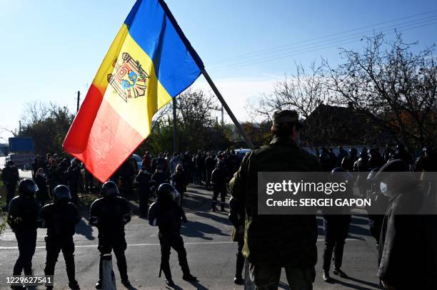 Man holds Moldovan national flag as special police officers patrol a street near a polling station during the second round of Moldova's presidential...