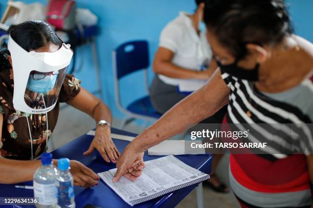 An illiterate voter uses her fingerprint to sign at a polling station in Igarape Miri, Para state, Brazil on November 15 during the first round of...