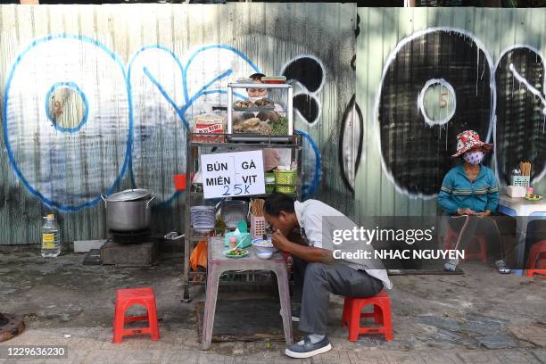 This photograph taken on September 8, 2020 shows a man eating a bowl of noodle soup from a street food vendor along a sidewalk in Ho Chi Minh city....