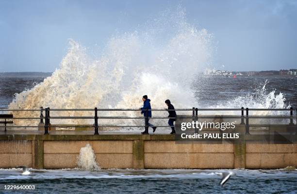 Waves break over a wall separating the marine lake from the sea at New Brighton in north west England on November 16, 2020 as high tide approaches.