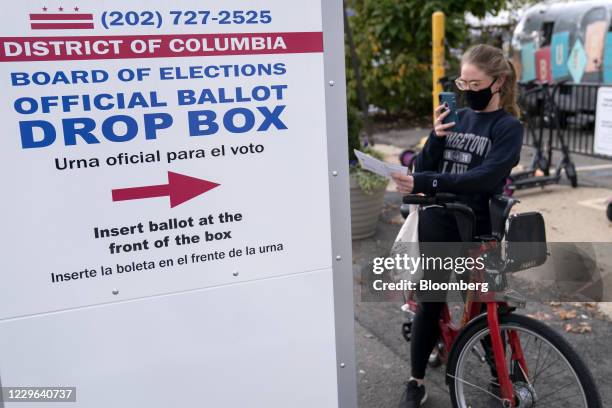 Bloomberg Best of the Year 2020: A voter wearing a protective mask photographs her ballot before depositing the vote into an Official Ballot Drop Box...