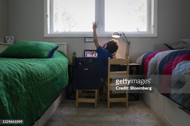Bloomberg Best of the Year 2020: A student raises his hand while attending an online class from home in Miami, Florida, U.S., on Thursday, Sept. 3,...