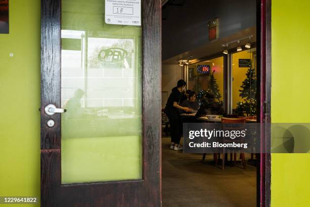 Waitress wearing a protective mask serves food to customers seated inside a restaurant in the Midtown neighborhood of Cleveland, Ohio, U.S., on...