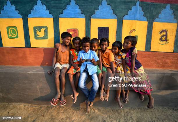 Children are seen watching a Cartoon movie on a Smartphone in front of a decorated wall with different Social Media symbol. Bandna is a traditional...
