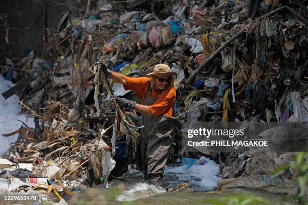 Willem Snyman from Fresh.ngo removes plastic deluge from litter trap nets and long line cables that was washed down under a bridge on the Clayville...