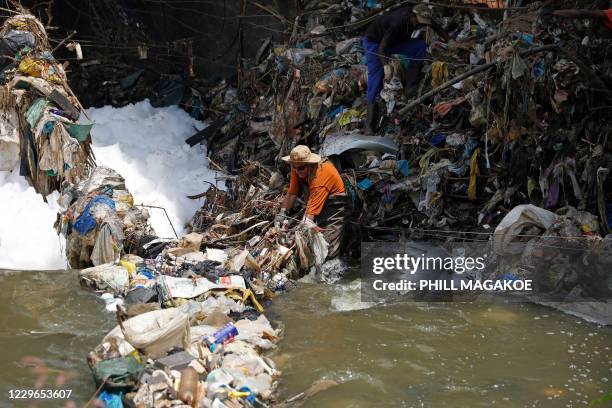 Willem Snyman from Fresh.ngo is assisted by a worker to remove plastic deluge from litter trap nets and long line cables that was washed down under a...