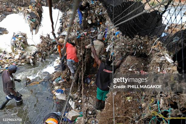 Workers from Fresh.ngo remove plastic deluge from litter trap nets and long line cables that was washed down under a bridge on the Clayville...