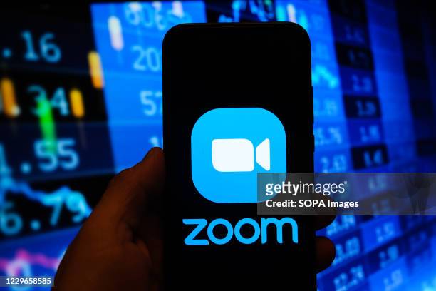 In this photo illustration a multiple exposure image shows a Zoom video logo displayed on a smartphone with stock market percentages in the...