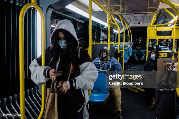 Commuters wear protective masks while riding a bus in New York, U.S., on Tuesday, Nov. 17, 2020. New York's Metropolitan Transportation Authority...