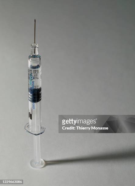 In this photo illustration - A flu vaccine syringe rests on a table on November 18, 2020 in Brussels, Belgium. The seasonal flu vaccine is made up of...