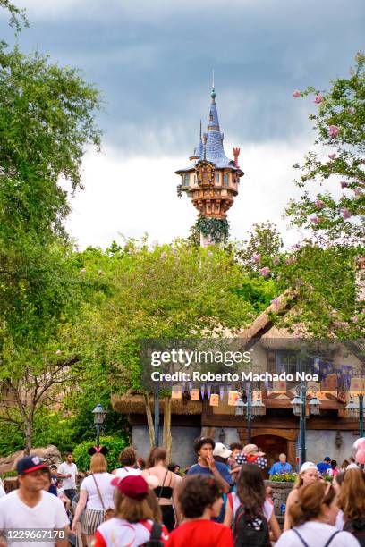 Group of people walking by the Rapunzel's Tower in the Walt Disney World theme park.