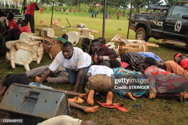 Supporters of Ugandan musician turned politician Robert Kyagulanyi, also known as Bobi Wine, take cover from tear gas as police officers arrest...