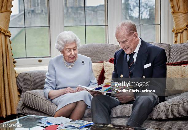 In this image released on November 19, Queen Elizabeth II and Prince Philip, Duke of Edinburgh look at their homemade wedding anniversary card, given...