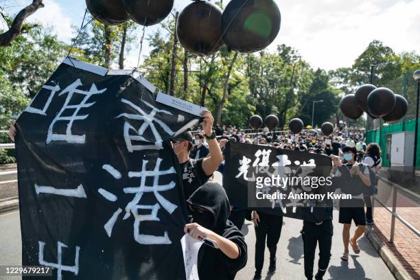 Students wearing black graduation gowns and Guy Fawkes masks march at the Chinese University of Hong Kong campus as they chant anti-government...