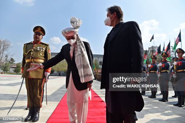 Afghan President Ashraf Ghani gestures to Pakistan's Prime Minister Imran Khan during a guard of honour ahead of their joint press conference at the...