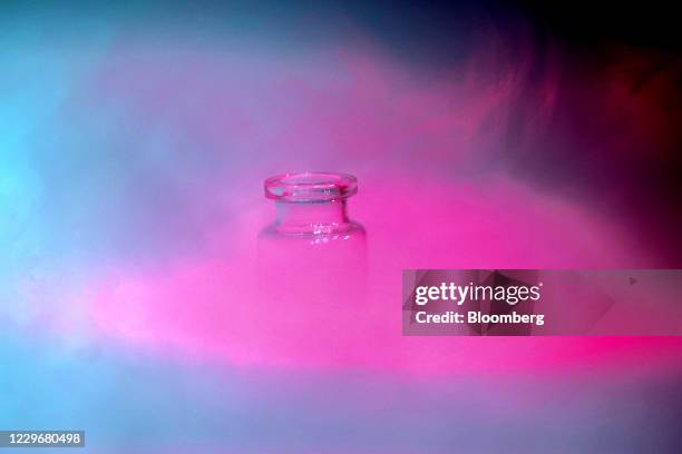 Glass medical vaccine vial in dry ice vapor in an arranged photograph in Wurzburg, Germany, on Wednesday, Nov. 18, 2020. Freezers required to store...