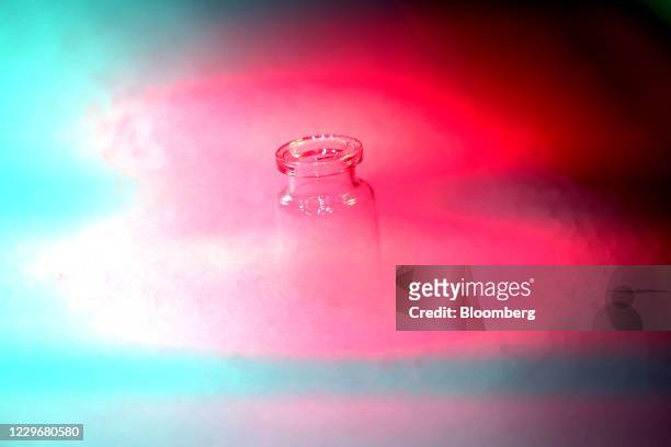 Glass medical vaccine vial in dry ice vapor in an arranged photograph in Wurzburg, Germany, on Wednesday, Nov. 18, 2020. Freezers required to store...