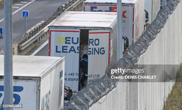 Migrant climbs into the back of lorries bound for Britain while traffic is stopped upon waiting to board shuttles at the entrance to the Channel...